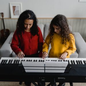 A woman and child playing piano together, enjoying a musical moment.